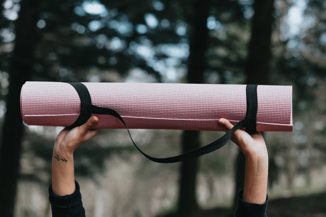 hands-hold-up-a-pink-yoga-mat-outdoors