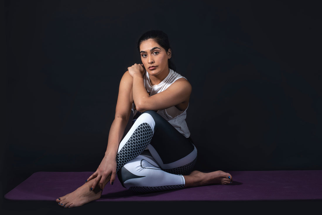 woman-sitting-in-yoga-pose-wearing-yoga-pants-and-crop-top-tshirt