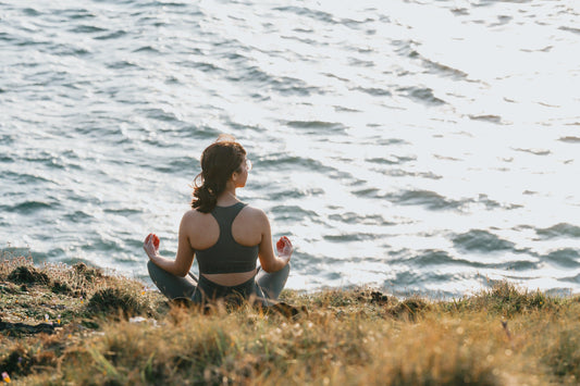 woman-sits-with-her-legs-crossed-facing-the-ocean