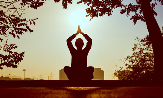 woman-sitting-in-the-park-practicing-yoga-poses-dusing-sunrise