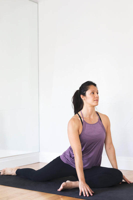 young-woman-doing-yoga-pose-against-white-wall