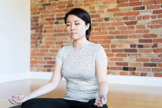 young-woman-doing-yoga-pose-and-meditating-in-front-of-brick-wall