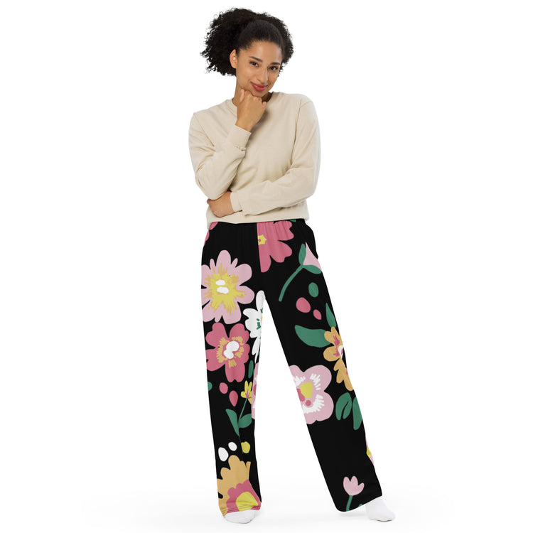 woman-posing-in-wide-leg-pants-with-colorful-flower-design-on dark-black-background