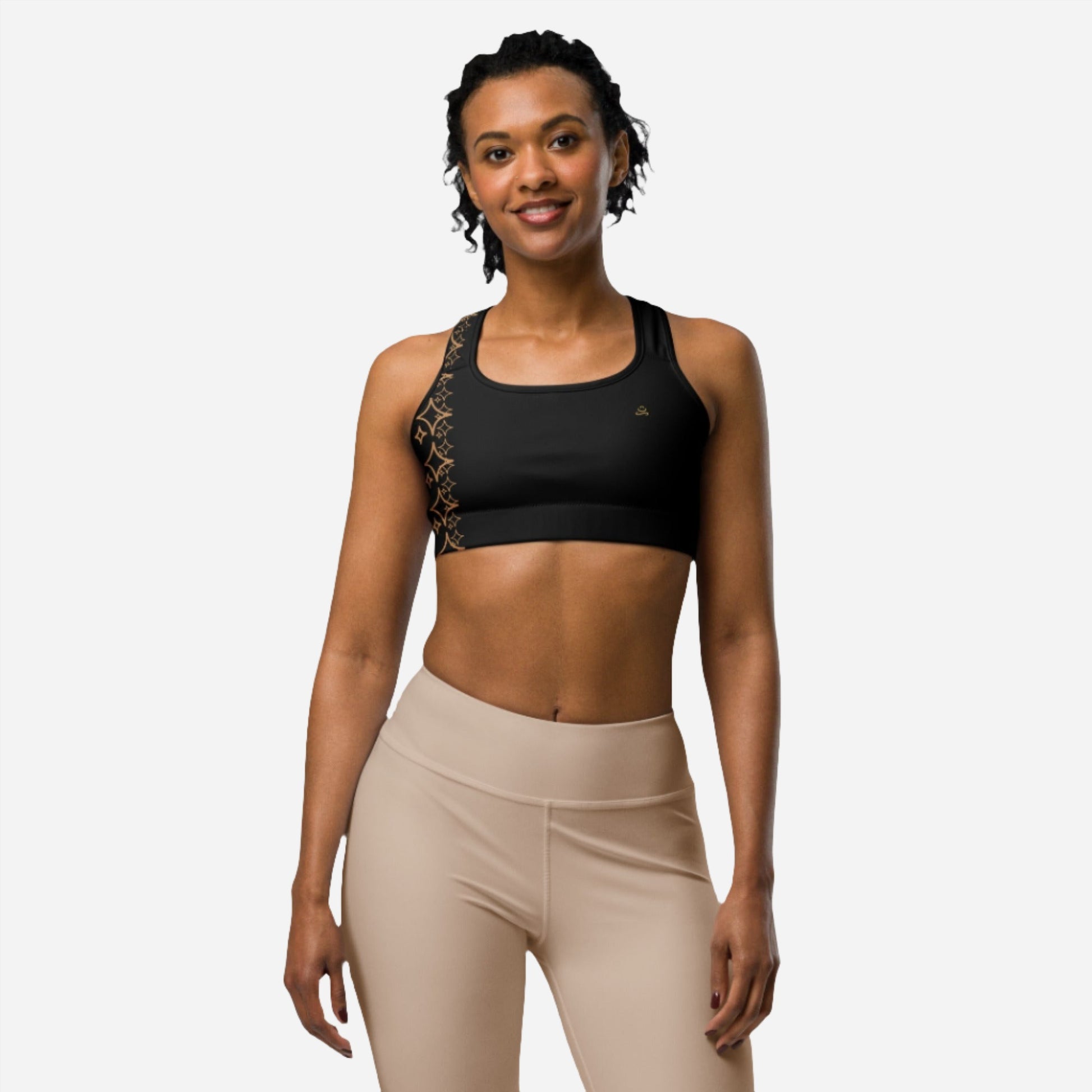 smiling woman posing in black racerback sports bra with golden design light background on 