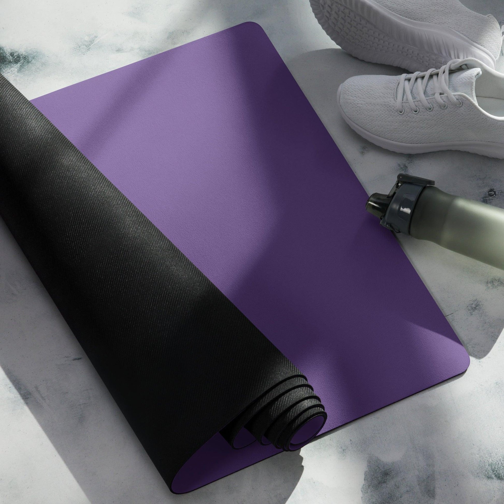 Purple yoga mat on the floor with white sports shoes and water bottle 